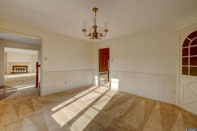 carpeted empty room featuring an inviting chandelier