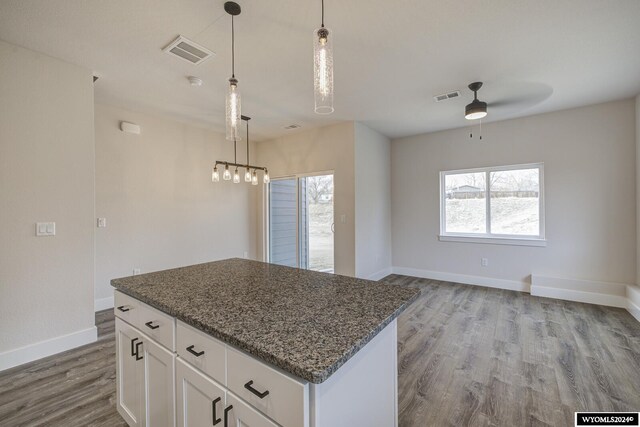 600 Badger Ln, Mills, WY 82644 - kitchen featuring dark stone counters, light hardwood / wood-style flooring, white cabinets, and hanging light fixtures