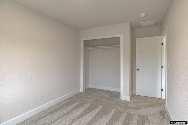 unfurnished bedroom with light colored carpet and a closet