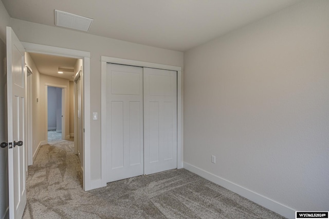 unfurnished bedroom featuring light carpet and a closet