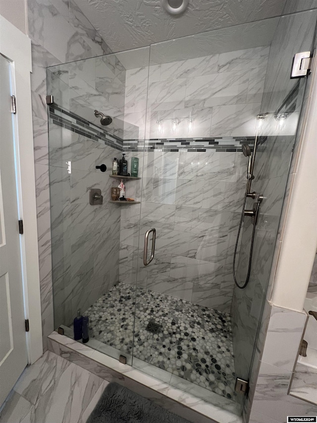 full bath with marble finish floor and a shower stall