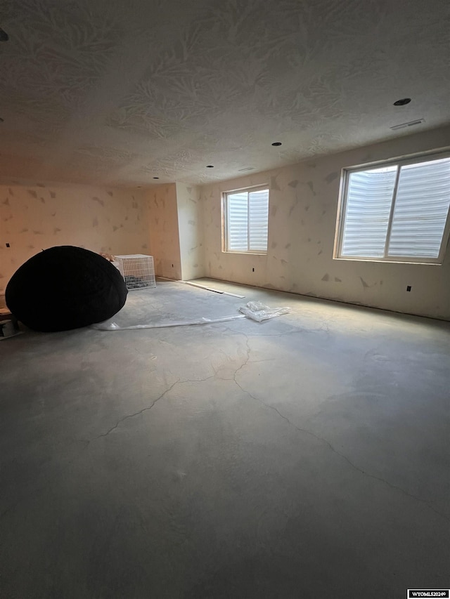 unfurnished room with visible vents, a textured ceiling, and unfinished concrete floors