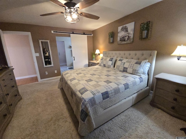 carpeted bedroom featuring ceiling fan and a barn door