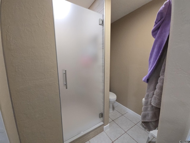 bathroom featuring a shower with shower door, tile patterned floors, and toilet