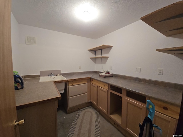 kitchen with sink, built in desk, kitchen peninsula, and a textured ceiling