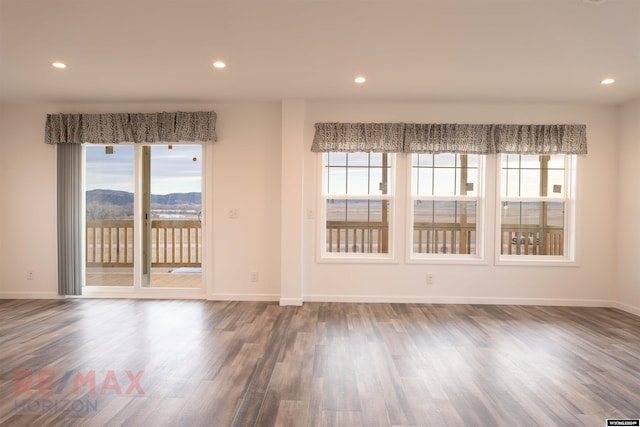 empty room with a mountain view, plenty of natural light, and dark hardwood / wood-style floors