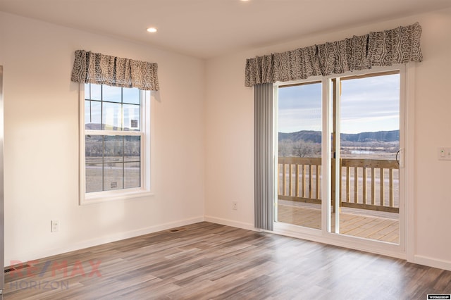 empty room featuring a mountain view and hardwood / wood-style flooring