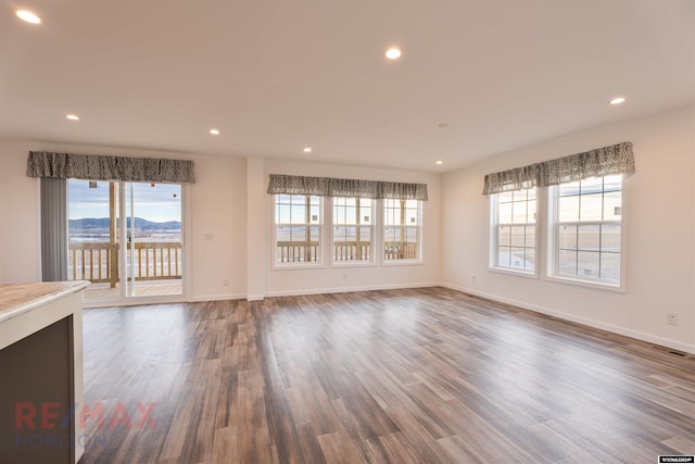 unfurnished living room featuring a mountain view, dark hardwood / wood-style flooring, and plenty of natural light