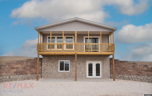 rear view of property featuring a balcony and french doors