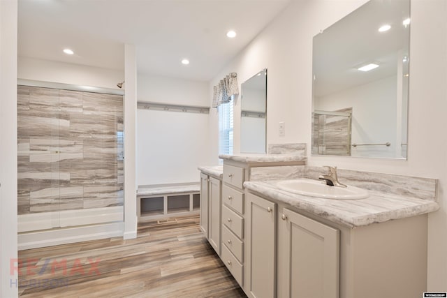 bathroom with hardwood / wood-style flooring, vanity, and a shower with door