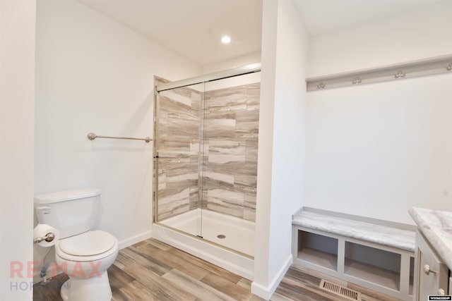 bathroom featuring hardwood / wood-style floors, vanity, toilet, and a shower with shower door