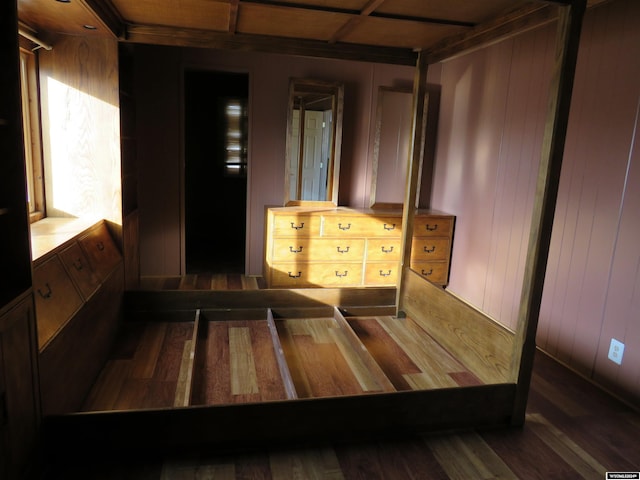 bedroom with dark wood-type flooring and wood walls