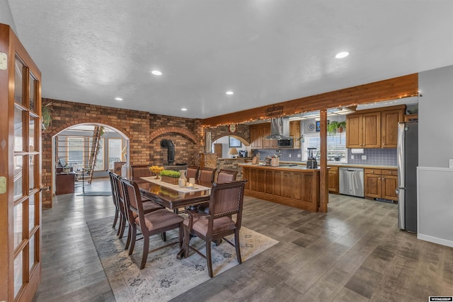 dining room with wood-type flooring, brick wall, and a wood stove