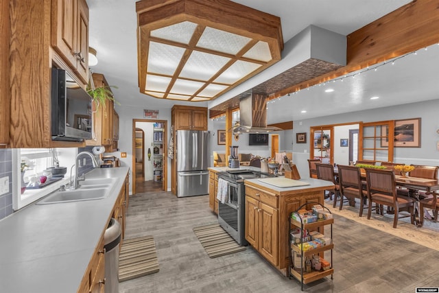 9 Spotted Tail Cir, Rock Springs, WY 82901 - kitchen featuring stainless steel appliances, island exhaust hood, light countertops, light wood finished floors, and brown cabinetry