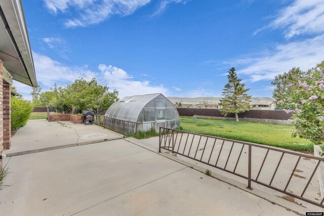 9 Spotted Tail Cir, Rock Springs, WY 82901 - fenced backyard featuring a greenhouse, a patio area, and an outbuilding
