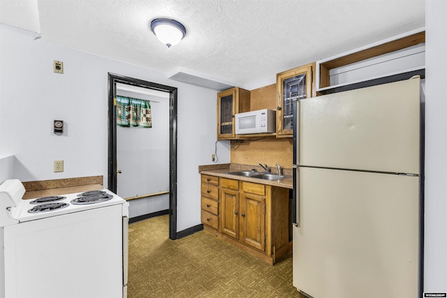 kitchen with a textured ceiling, sink, dark carpet, and white appliances