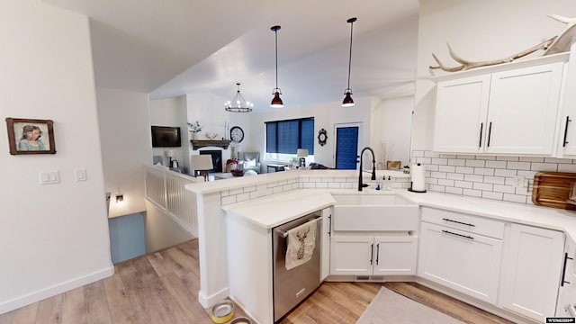 kitchen featuring kitchen peninsula, light wood-type flooring, stainless steel dishwasher, and hanging light fixtures