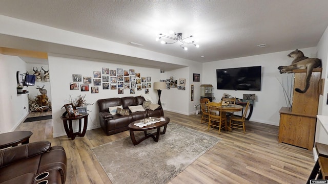 living room featuring wood-type flooring, a textured ceiling, and an inviting chandelier