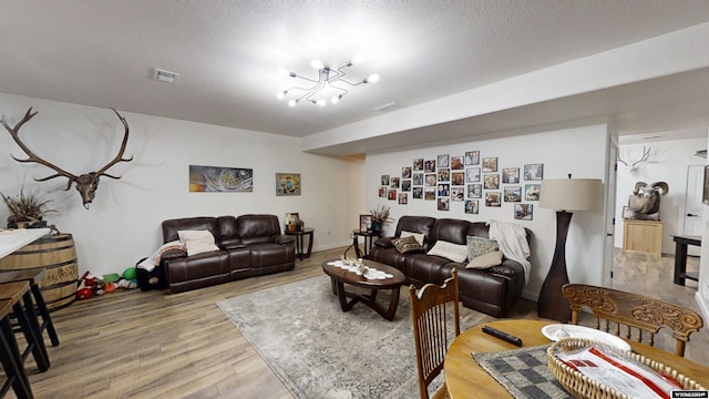 living room featuring hardwood / wood-style flooring, a textured ceiling, and a chandelier