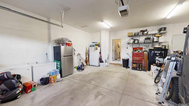 garage featuring white refrigerator, a garage door opener, and stainless steel refrigerator