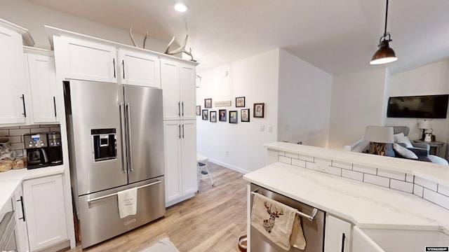 kitchen with high end refrigerator, decorative light fixtures, and white cabinetry