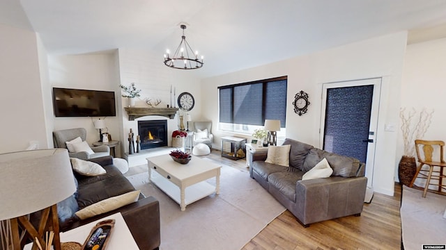 living room with a notable chandelier, light hardwood / wood-style floors, and vaulted ceiling