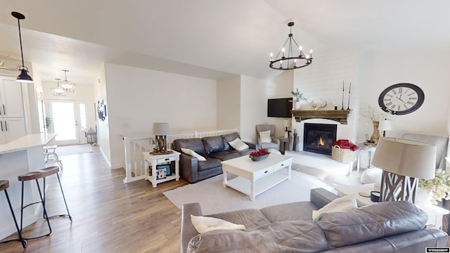 living room featuring light hardwood / wood-style flooring, lofted ceiling, and a notable chandelier