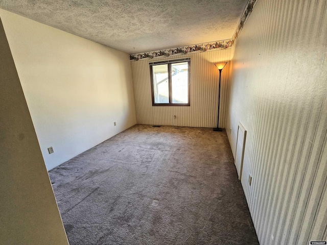 carpeted spare room with a textured ceiling