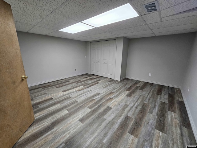 basement featuring a drop ceiling and wood-type flooring