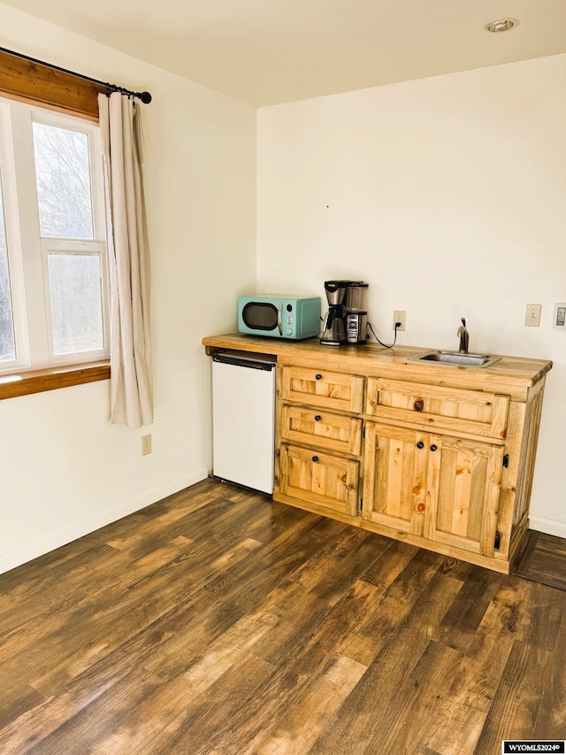 kitchen with light brown cabinets, white appliances, dark hardwood / wood-style floors, and sink