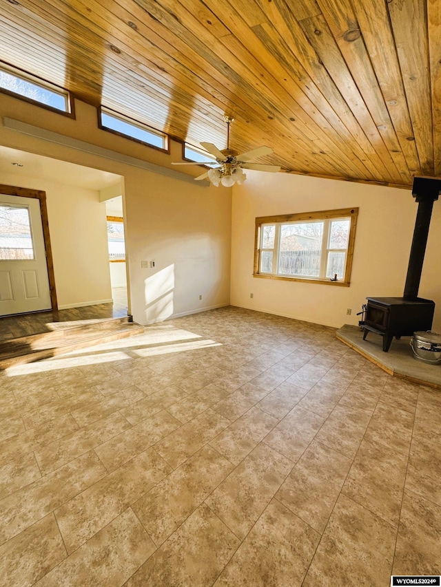 unfurnished living room featuring a wood stove, ceiling fan, wooden ceiling, and lofted ceiling