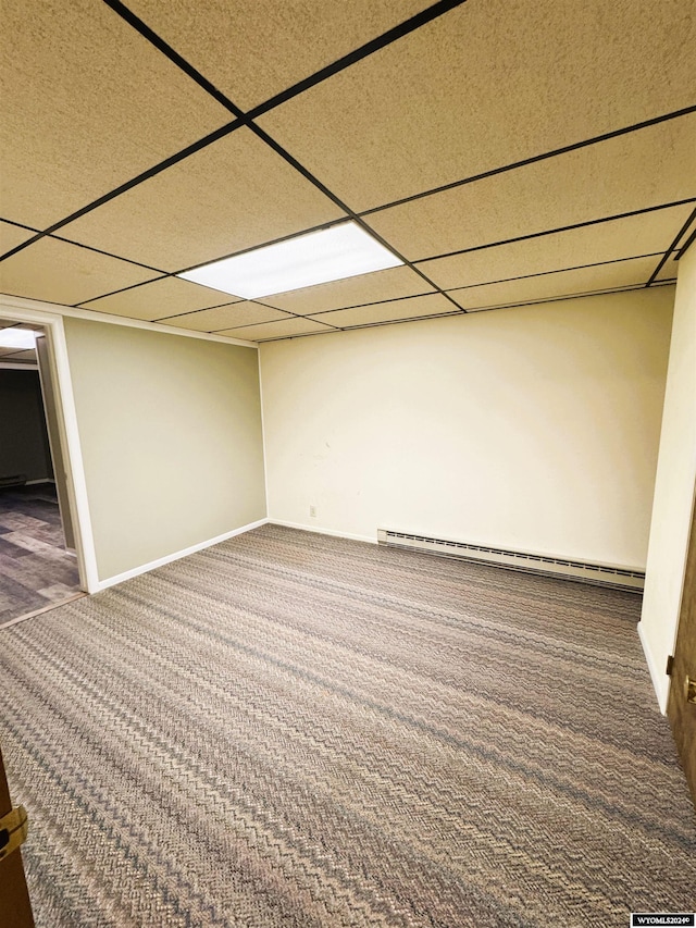 basement featuring a paneled ceiling, dark carpet, and a baseboard radiator