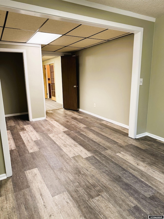 empty room with a drop ceiling and hardwood / wood-style flooring