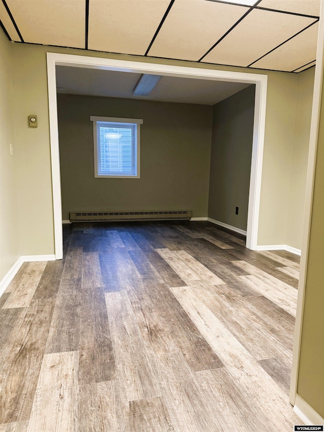 unfurnished room featuring hardwood / wood-style floors and a baseboard heating unit