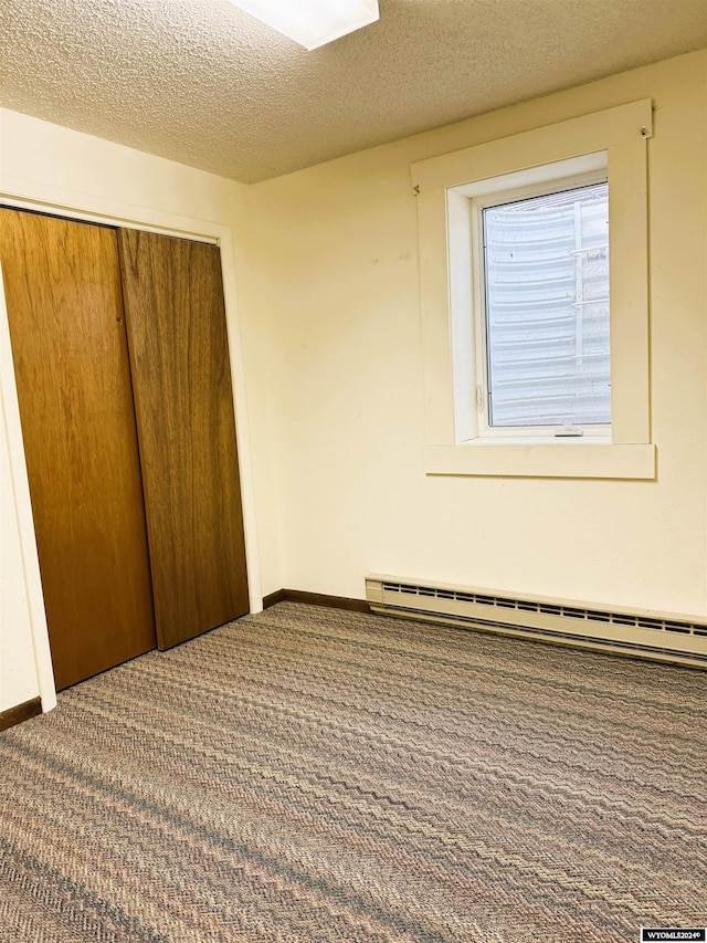 unfurnished bedroom with carpet flooring, a textured ceiling, a baseboard radiator, and a closet