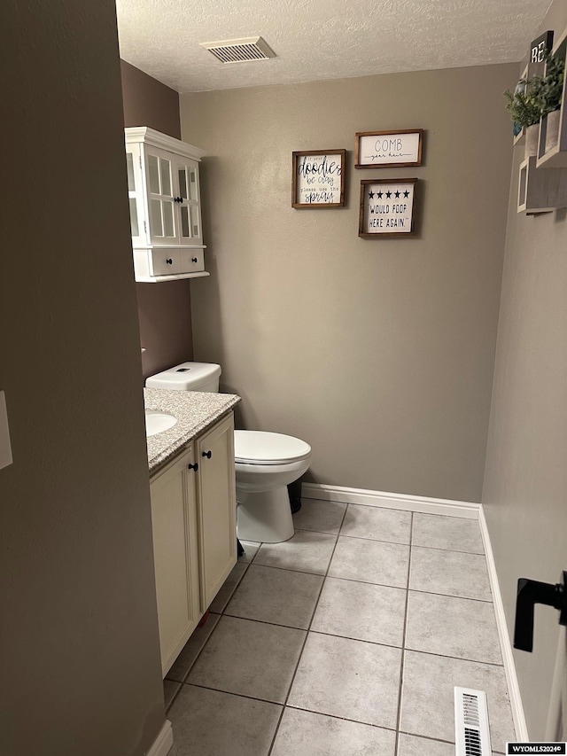 bathroom with tile patterned floors, vanity, toilet, and a textured ceiling