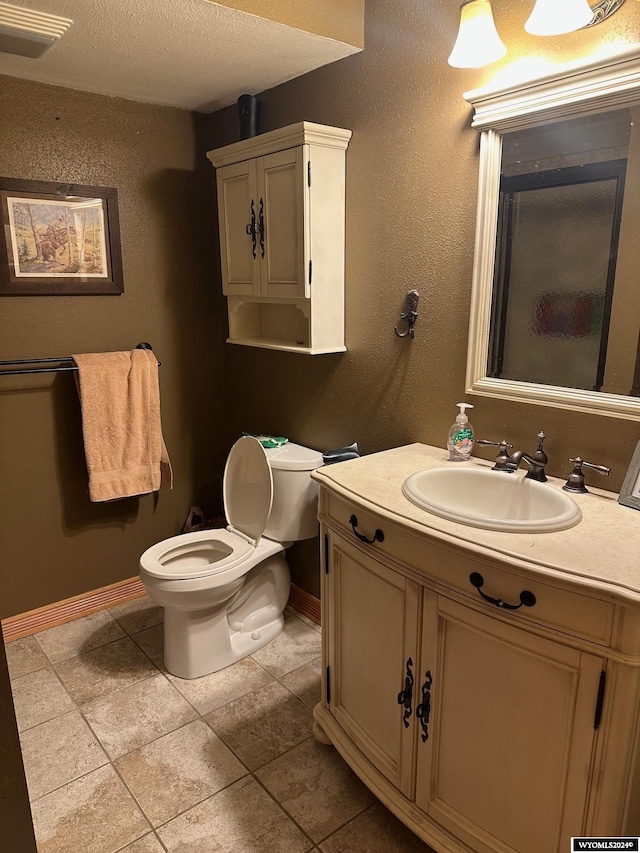 bathroom with tile patterned floors, vanity, a textured ceiling, and toilet