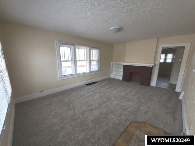 unfurnished living room featuring a textured ceiling and carpet floors