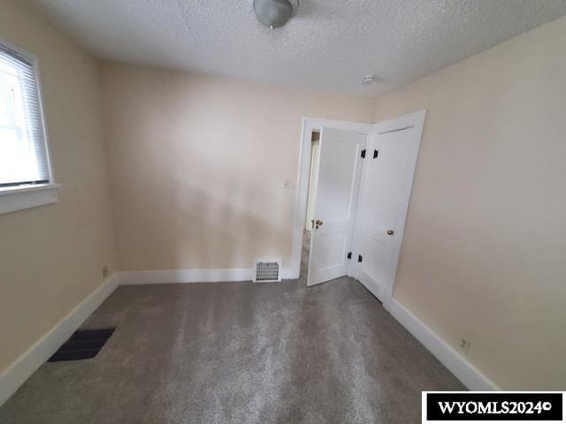 carpeted empty room with a textured ceiling