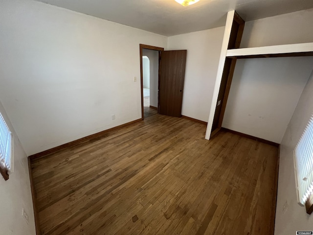 unfurnished bedroom with multiple windows, a closet, and hardwood / wood-style floors