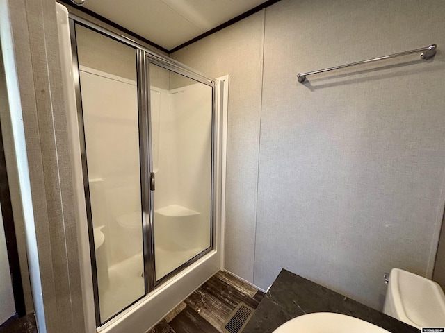 bathroom with hardwood / wood-style floors, toilet, and a shower with shower door