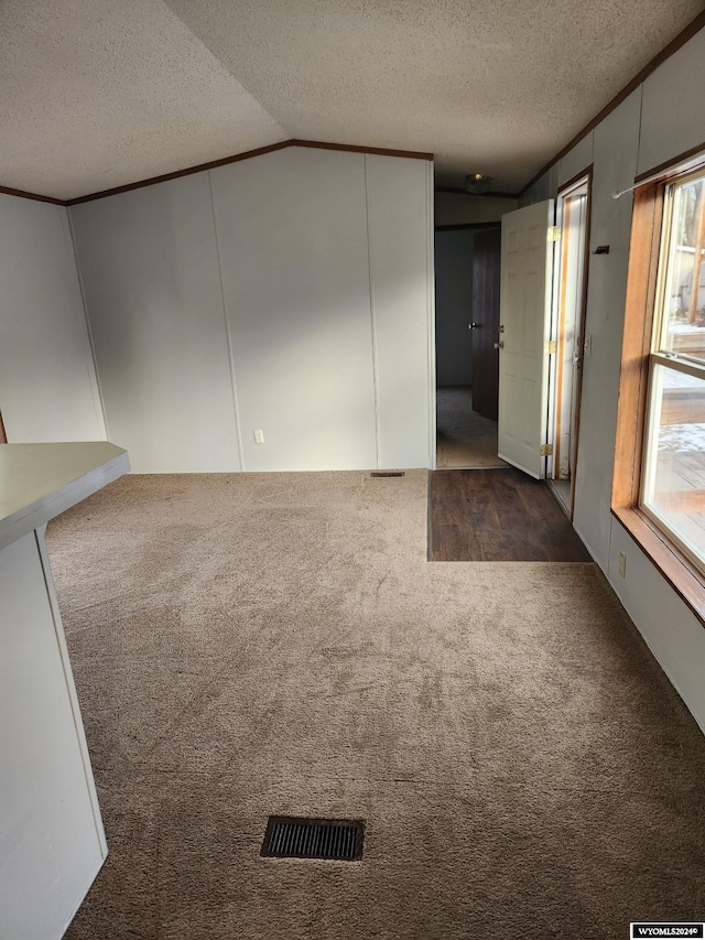 spare room featuring dark carpet, a textured ceiling, and vaulted ceiling