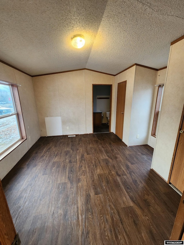 unfurnished room featuring dark hardwood / wood-style flooring, a textured ceiling, and vaulted ceiling