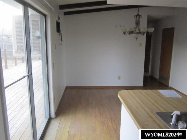 unfurnished dining area featuring a chandelier and hardwood / wood-style flooring