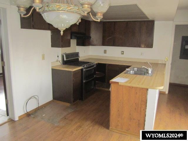 kitchen with kitchen peninsula, light wood-type flooring, black range oven, sink, and range hood