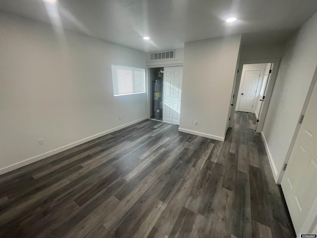 unfurnished bedroom featuring electric water heater, a closet, and dark hardwood / wood-style floors