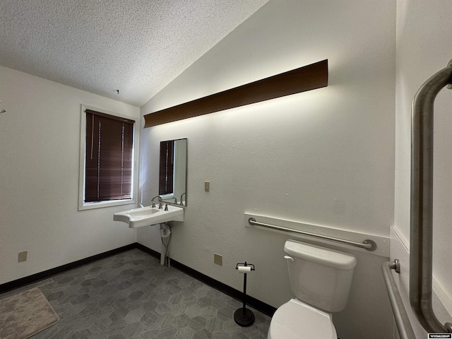 bathroom with sink, toilet, a textured ceiling, and vaulted ceiling