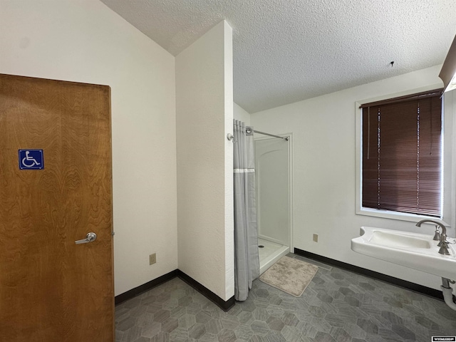 bathroom with lofted ceiling, a textured ceiling, and walk in shower