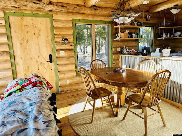 dining room with beam ceiling, wood-type flooring, and rustic walls