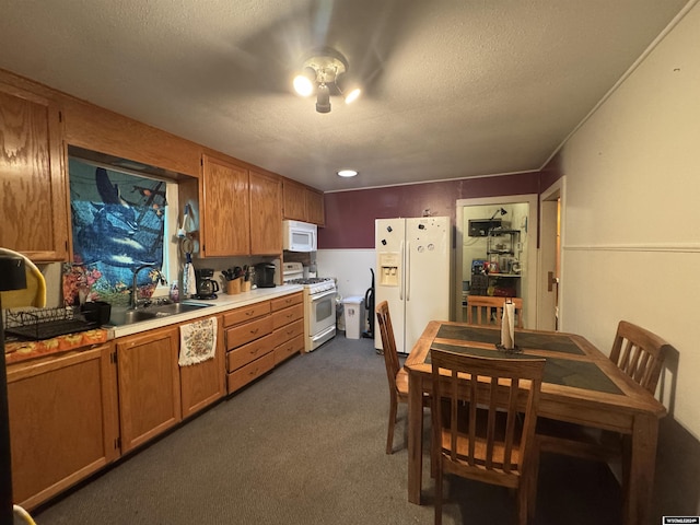 kitchen with a textured ceiling, sink, white appliances, and dark colored carpet